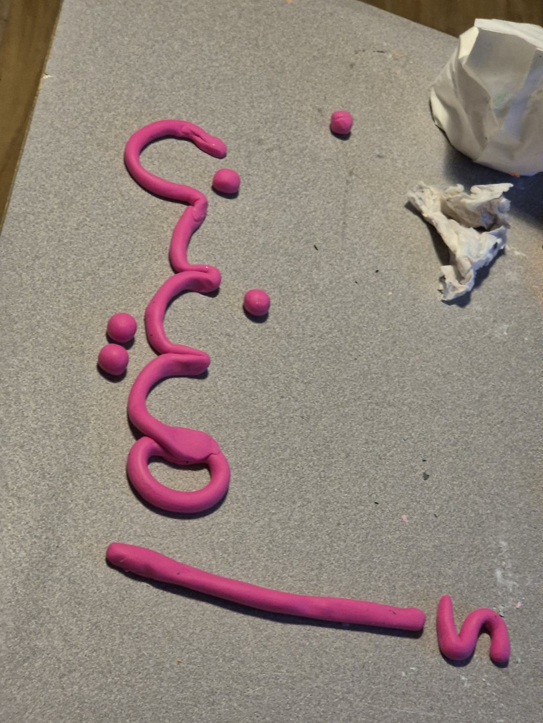 Lettres arabes en pâte à modeler rose sur la table