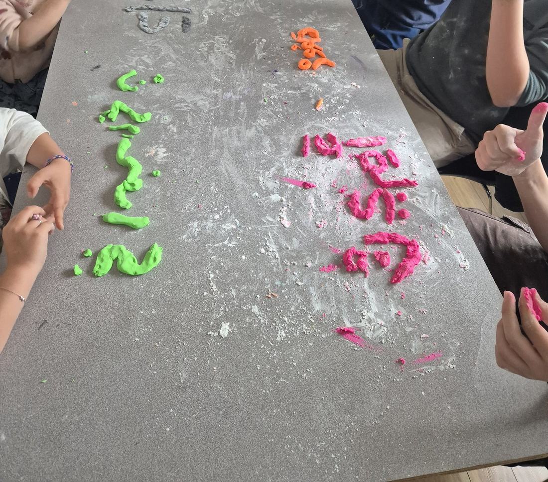 Enfants formant des lettres arabes en pâte à modeler colorée