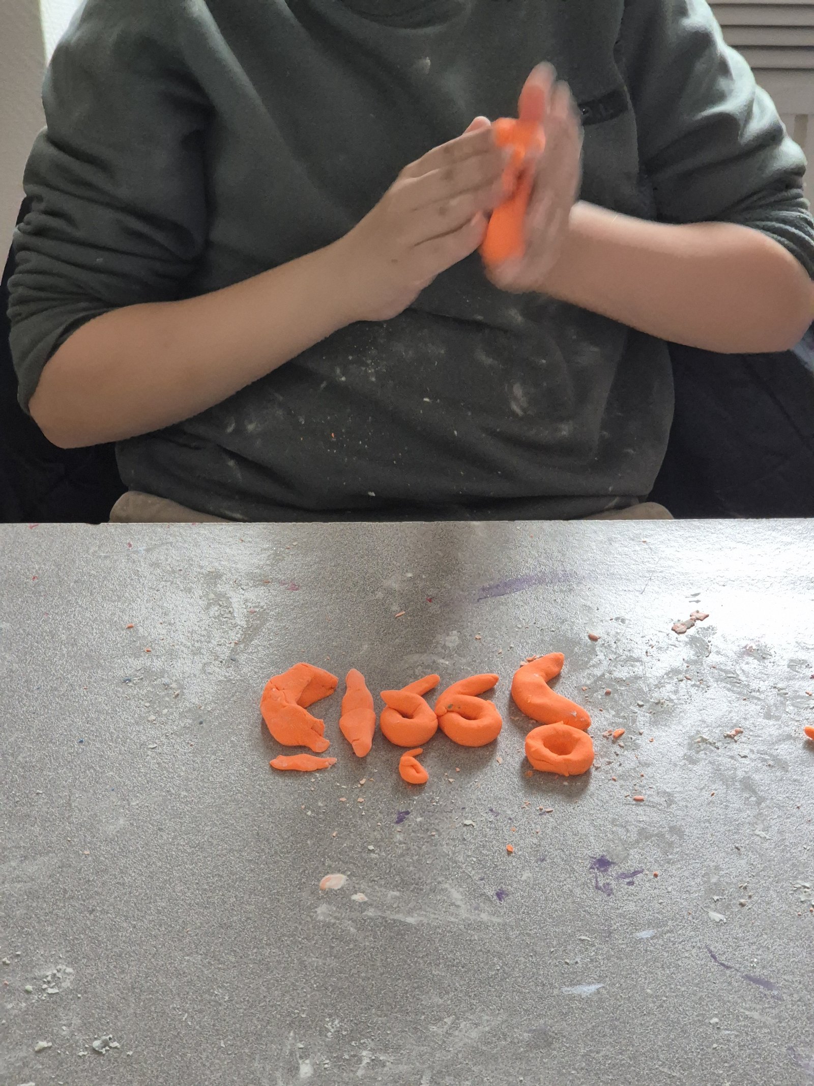 Un enfant façonne une lettre arabe en pâte à modeler